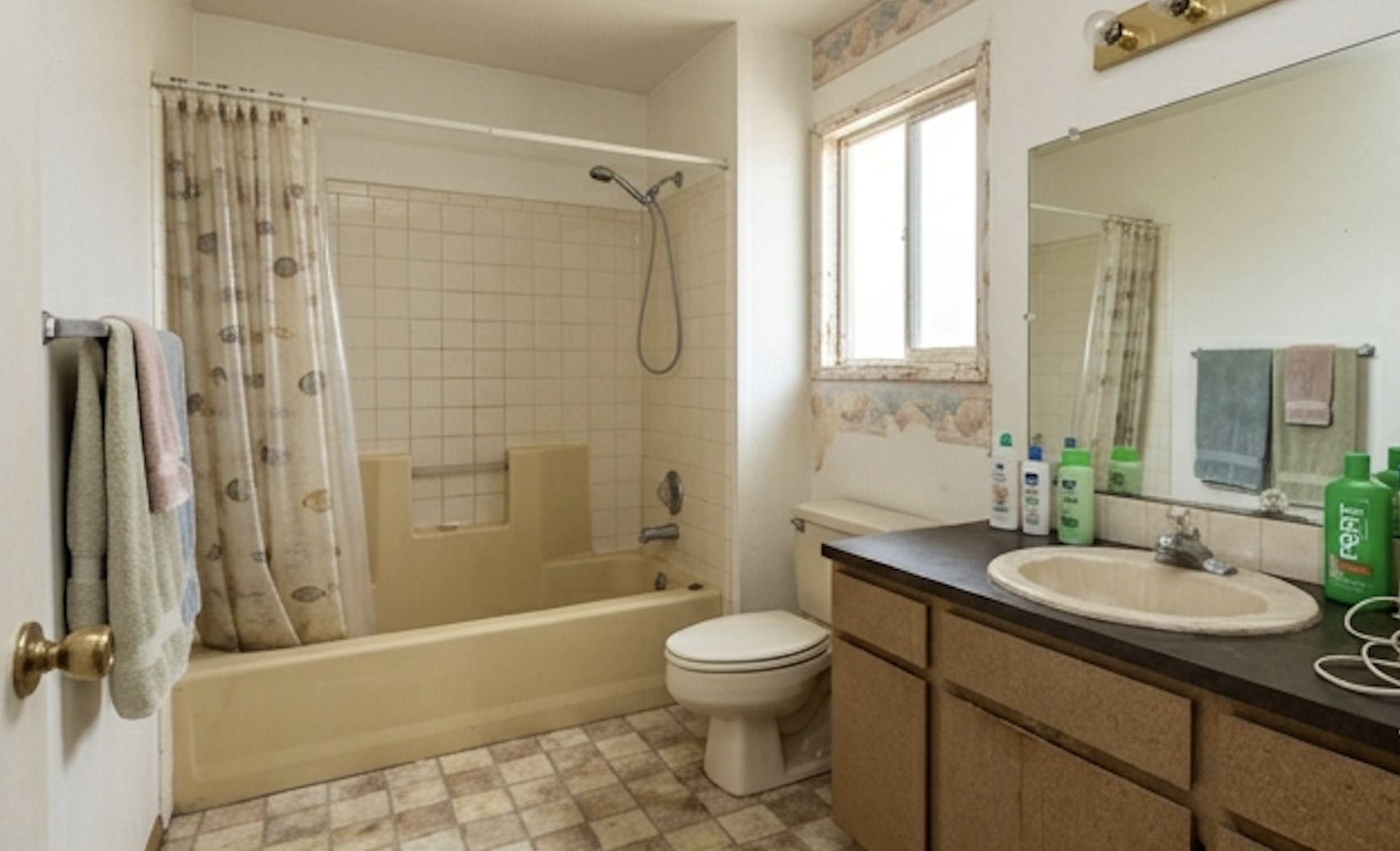 Guest bathroom before modernization with dated tub surround, older vanity, and worn finishes